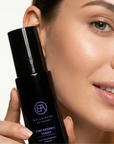 Woman holding a Bella Aura skincare product close to her face