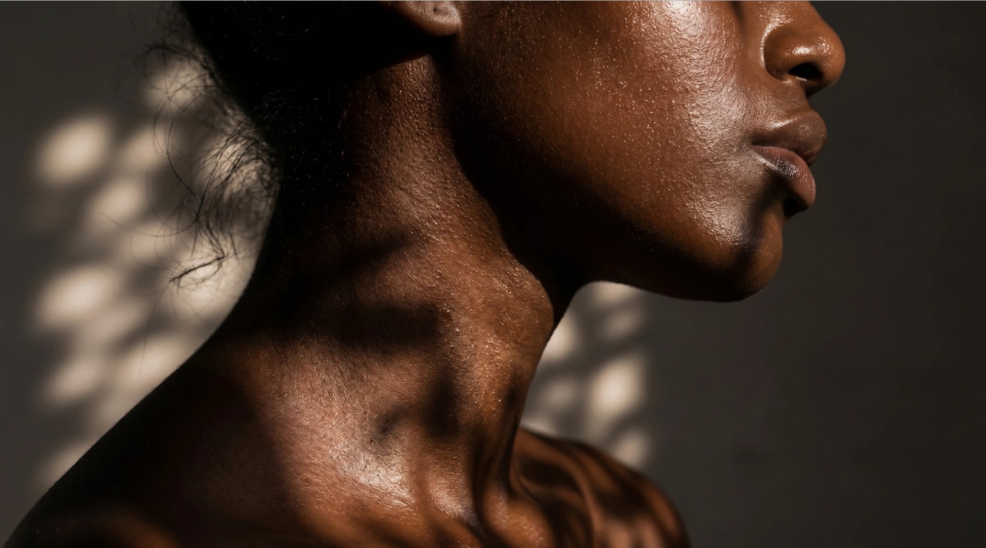 Side profile of a person with a dark skin tone against a blurred background